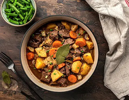 Bowl of beef casserole with vegetables on a wooden table