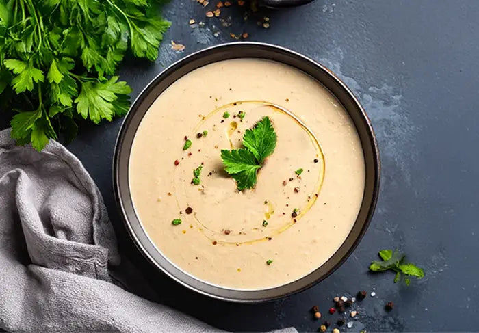 Bowl of creamy mushroom soup with herbs and a drizzle of truffle oil on a dark surface