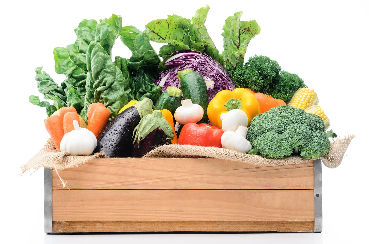 Wooden crate filled with a variety of fresh vegetables on a white background