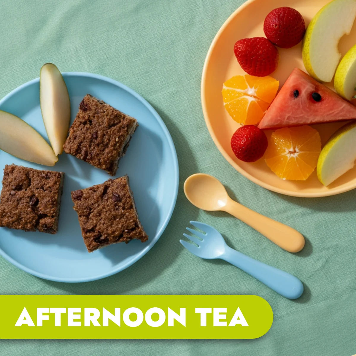 An aerial view photo of a child's place setting. One plate has 3 square pieces of healthy Weetbix and chocolate slice with 2 slices of pear on the side. A second plate shows a colourful and fresh fruit platter of watermelon, strawberries and pear slices. The food is aimed at young children.