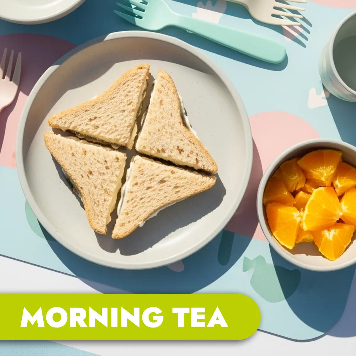 Triangular CREAM CHEESE AND VEGEMITE sandwiches on a plate with a bowl of fruit and 'Morning Tea' text.