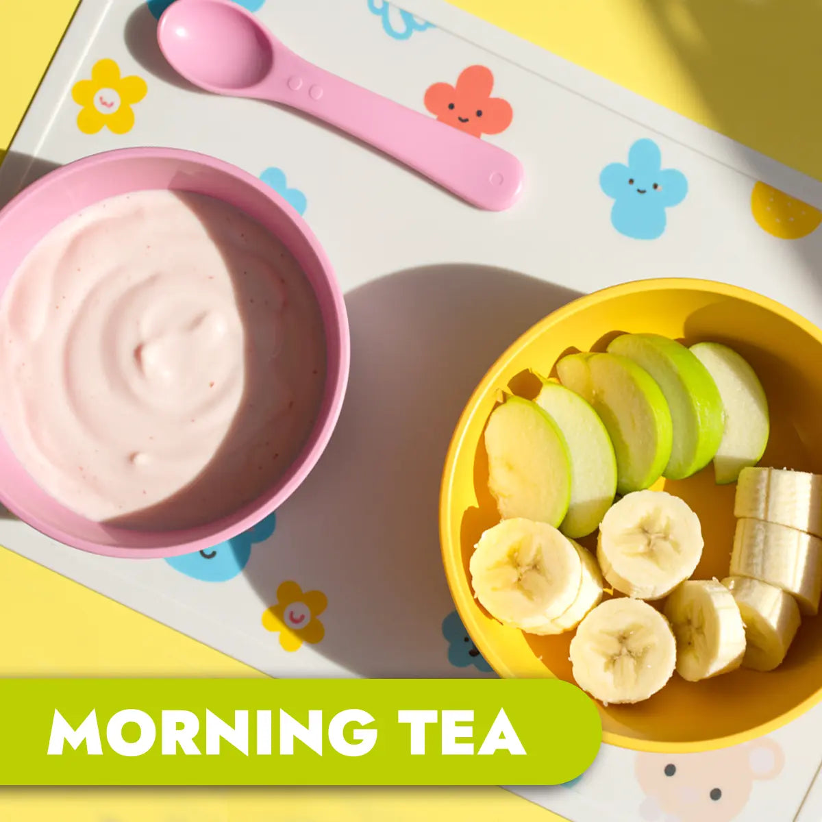 Children's morning tea with yogurt, apple slices, and banana on a colorful tray.
