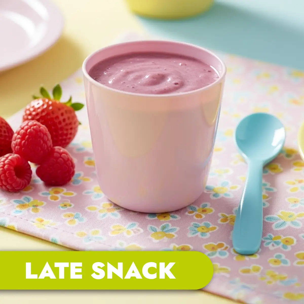 TLG Childcare meals. Pink cup of berry smoothie with strawberries and a blue spoon on a floral tablecloth, labeled 'LATE SNACK'.