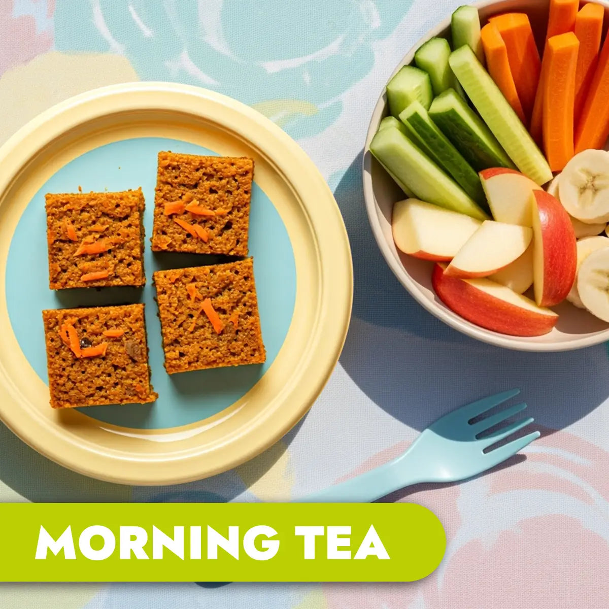 TLG Childcare catering. Morning tea with carrot cake squares and fruit on a colorful tablecloth