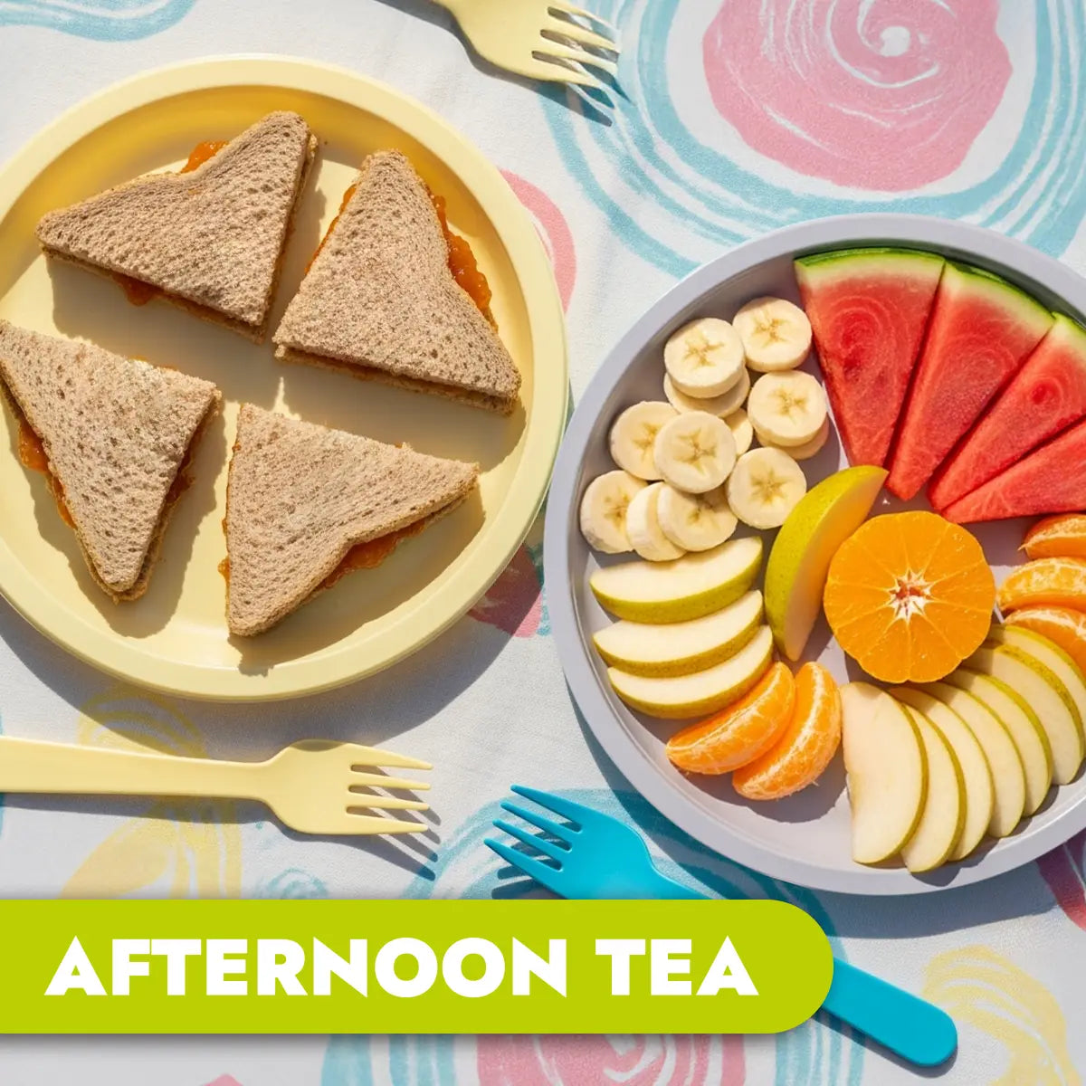 TLG Childcare meals. Afternoon tea setup with sandwiches and a fruit platter on a colorful tablecloth.